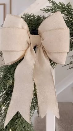 a christmas wreath with a bow hanging from it's side on a stair rail