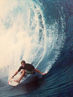 a man riding a wave on top of a surfboard in the ocean with blue water