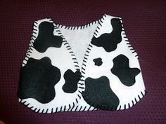 two pieces of cloth with black and white cow prints on them sitting on a purple surface