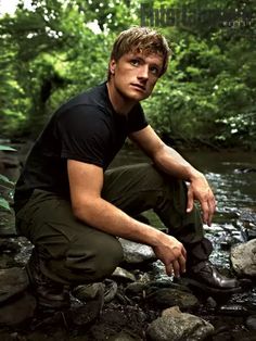 a man squatting on rocks next to a river