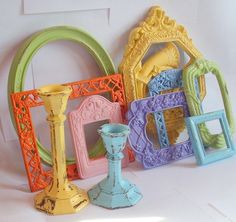 there are many different colored vases and frames on the table, including one with a candle holder