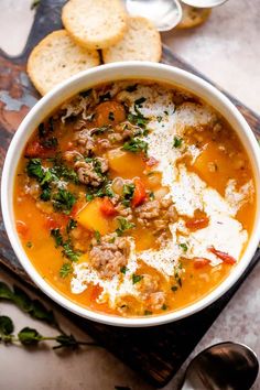 a bowl of soup with bread and parmesan cheese on the side, ready to be eaten