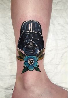 a tattoo on the leg of a person with a darth vader helmet and flowers