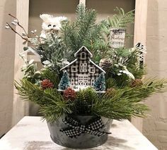 a potted plant filled with pine cones and greenery on top of a table