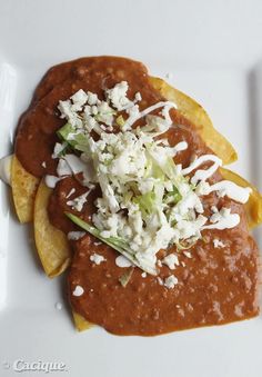 a white plate topped with chili cheese and tortilla chips on top of it