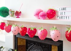 some paper strawberries are hanging on a mantle