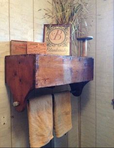 an old wooden shelf with towels hanging from it's sides and a plant in the corner