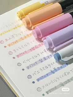 four different colored pens sitting on top of an open notebook with japanese writing in it