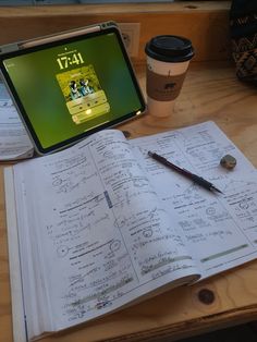 a laptop computer sitting on top of an open book next to a cup of coffee