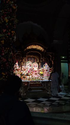 a group of people standing in front of a small shrine with statues on the floor