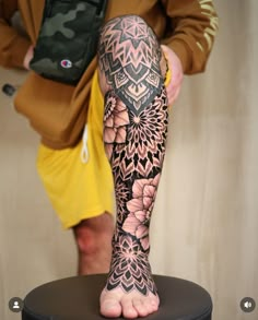 a person standing on top of a stool with a flower tattoo on their arm and leg