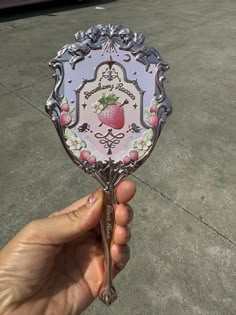 a hand holding a pink and white plate with a strawberry on it