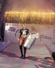 a woman holding a metal bucket on top of a stage