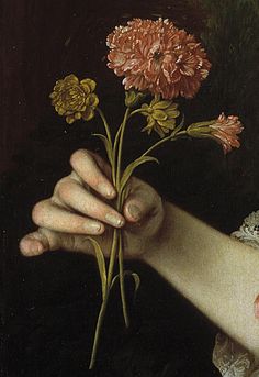 a close up of a person's hand holding flowers in front of a painting