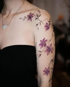 a woman wearing a black dress with purple flowers on her left arm and shoulder tattoo