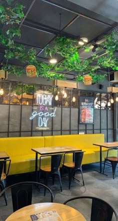 the inside of a restaurant with yellow booths and green plants hanging from the ceiling above