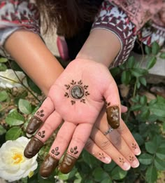 two hands with henna designs on them, one is holding the other's hand