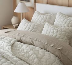 an unmade bed with white comforter and pillows