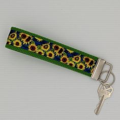 a key fobring with sunflowers on it and a green ribbon around the clasp