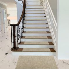 there is a staircase leading up to the second floor in this house with marble floors and white walls