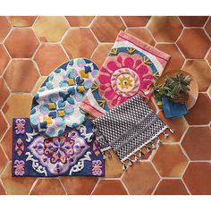 three towels and two pot holders on a tile floor next to a planter with succulents