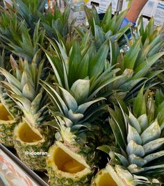 several pineapples cut in half on display at a grocery store, with the tops peeled off