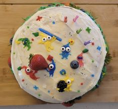 a birthday cake decorated with cartoon characters and decorations on top of a wooden table next to a knife