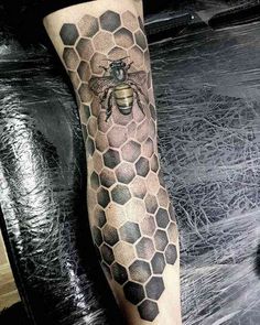 a man's leg with a bee and honeycomb tattoo on it