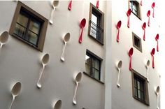 spoons hanging from the side of a building with red and white ribbons on them