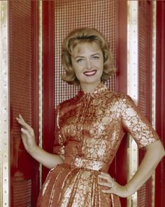 a woman standing in front of a red door with her hands on her hips and smiling at the camera