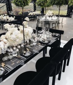 the tables are set with black chairs and white flowers