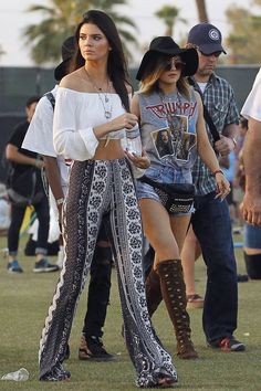 two women in high waisted pants and cowboy boots are walking through the grass with other people