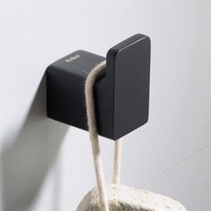 a rock with a rope hanging from it's side next to a white wall