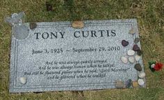 a headstone on the ground with stones and flowers around it that says tony curtis