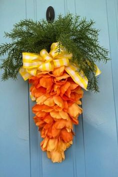 an orange and yellow wreath hanging on a blue door