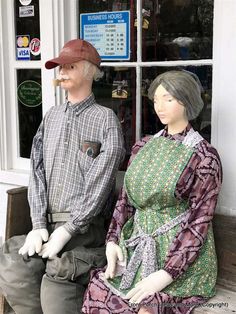 two mannequins sitting on a bench in front of a store