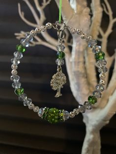 a green beaded bracelet hanging from a tree with a white branch in the background