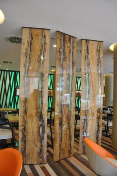 the interior of a restaurant with wood panels and orange chairs in front of windows that have green glass coverings on them