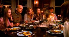 a group of people sitting around a table with food and candles in front of them