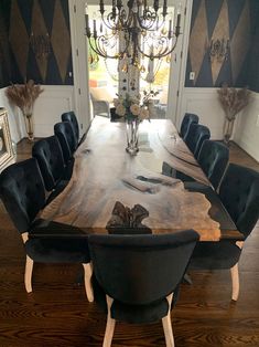 a dining room table with black chairs and a chandelier hanging from the ceiling