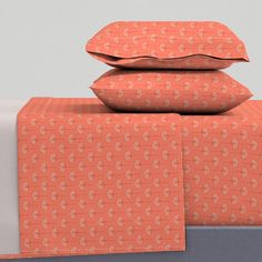 three pillows are stacked on top of each other in front of an orange and white bed