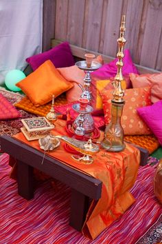 the table is covered with colorful pillows and other decorative items, including an oil lamp