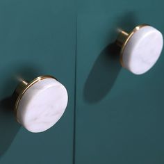 two white and gold knobs on a green cabinet