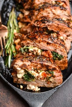 grilled pork chops and vegetables on a black plate with a fork next to it