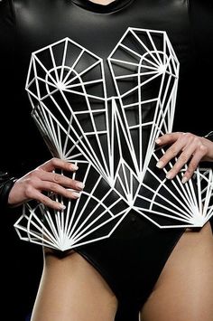 a woman in a black bodysuit with white geometric designs on her chest and arms