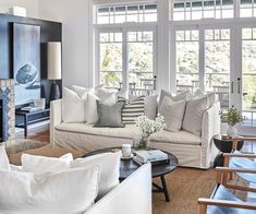 a living room filled with white furniture and lots of windows covered in blue paint on the walls