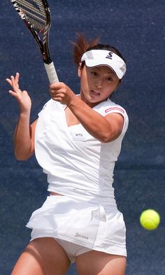 a female tennis player is swinging her racket to hit the ball with her racquet