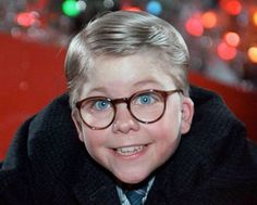 a young boy wearing glasses and a coat with lights in the back ground behind him