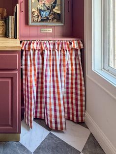 a painting hangs on the wall above a checkered table cloth draped in front of it