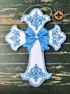 a blue and white cross ornament with a bow on it's side